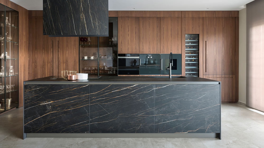 Cucina con piano top in laminato effetto marmo scuro abbinato a colonne a parete effetto legno