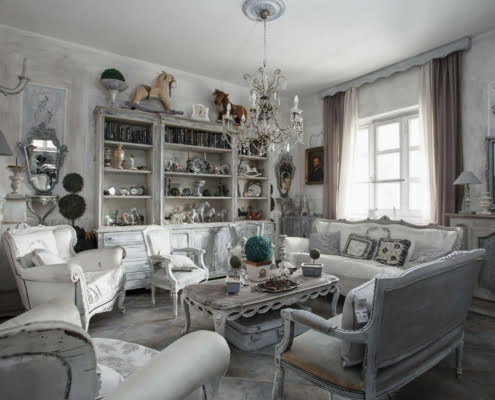 Salotto in stile shabby chic dai mobili rustici e raffinati luminoso grazie al colore bianco e alla grande finestra da cui entra la luce